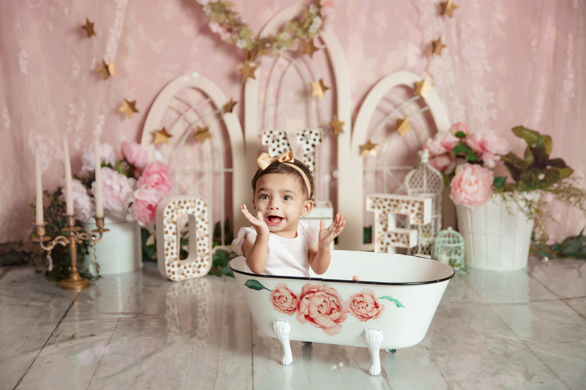 Happy girl in floral tub after a cake smash