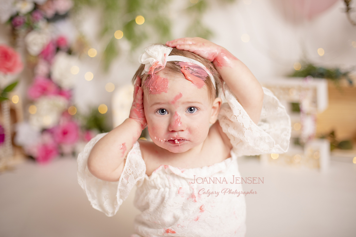 birthday photoshoot for baby girl with pink and white flowers at a cake smash