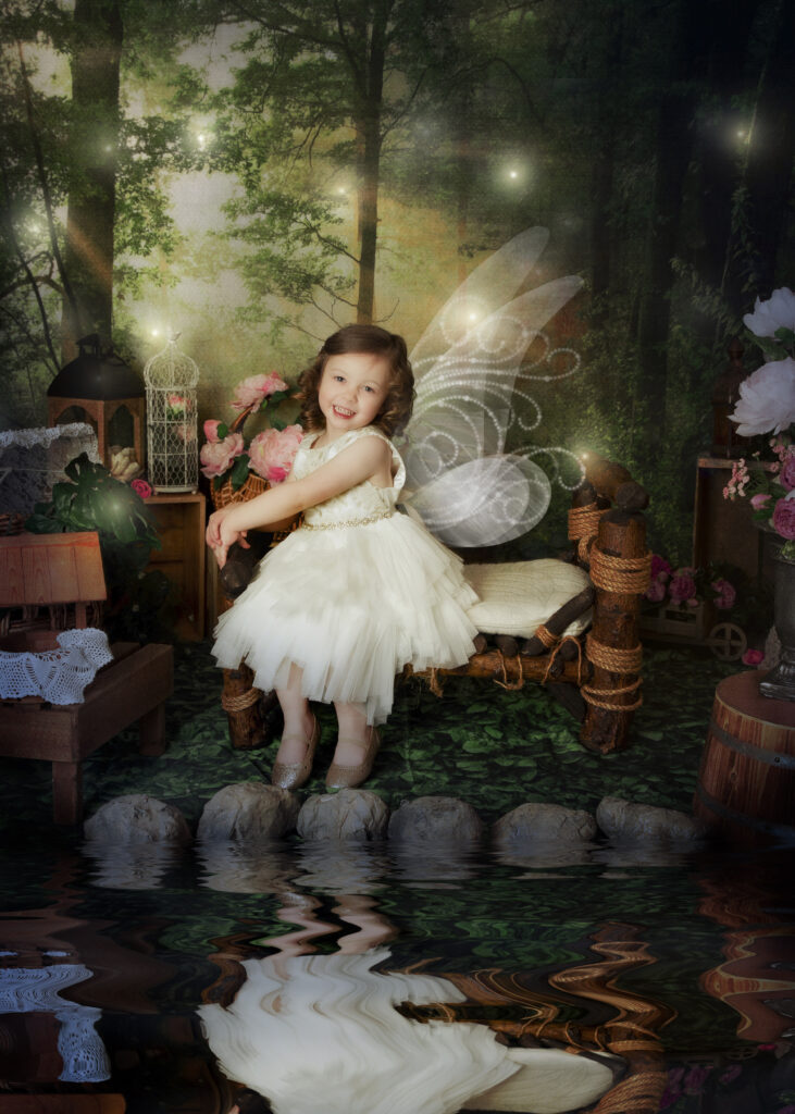 Fairytale photoshoot of little girl in white dress with fairy wings