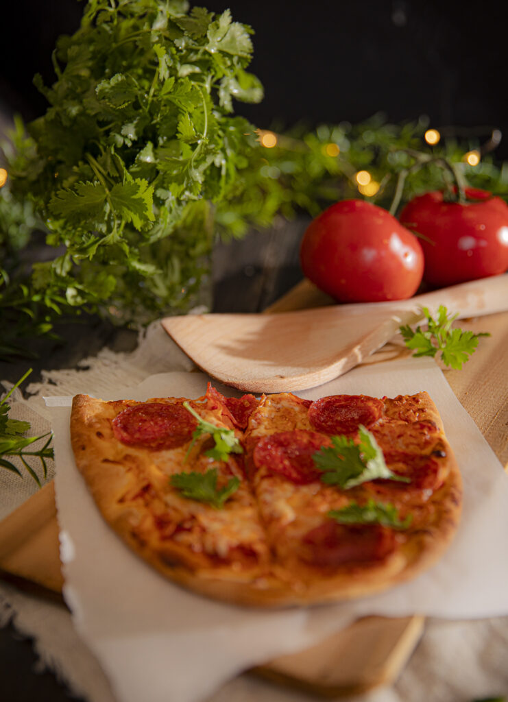 Delicious side view of a mini pepperoni pizza with cilantro