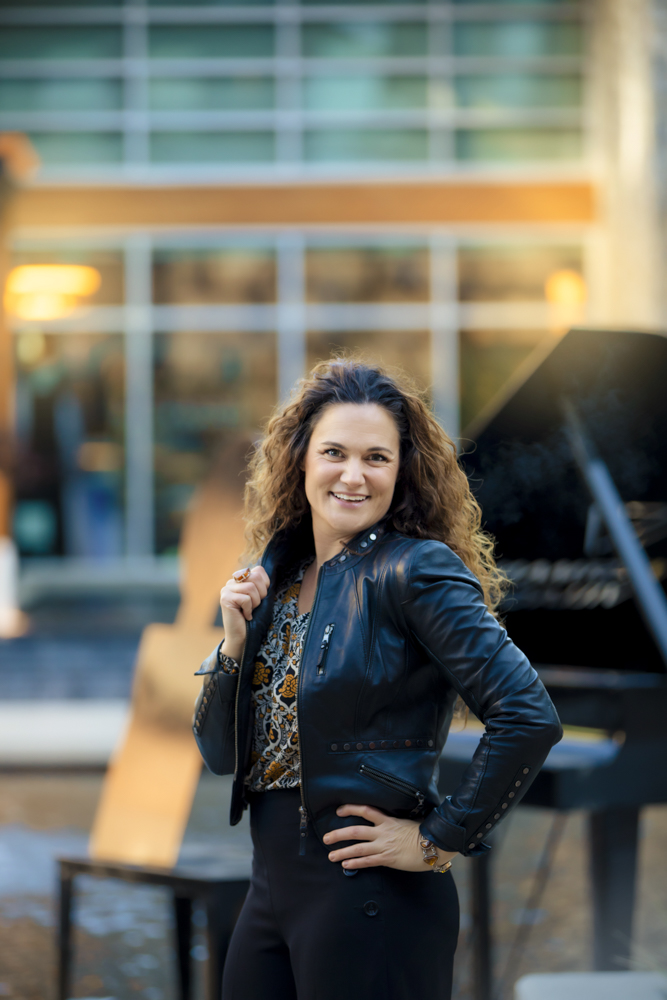 Kristen Scott, Calgary musician and teacher standing happily in front of piano