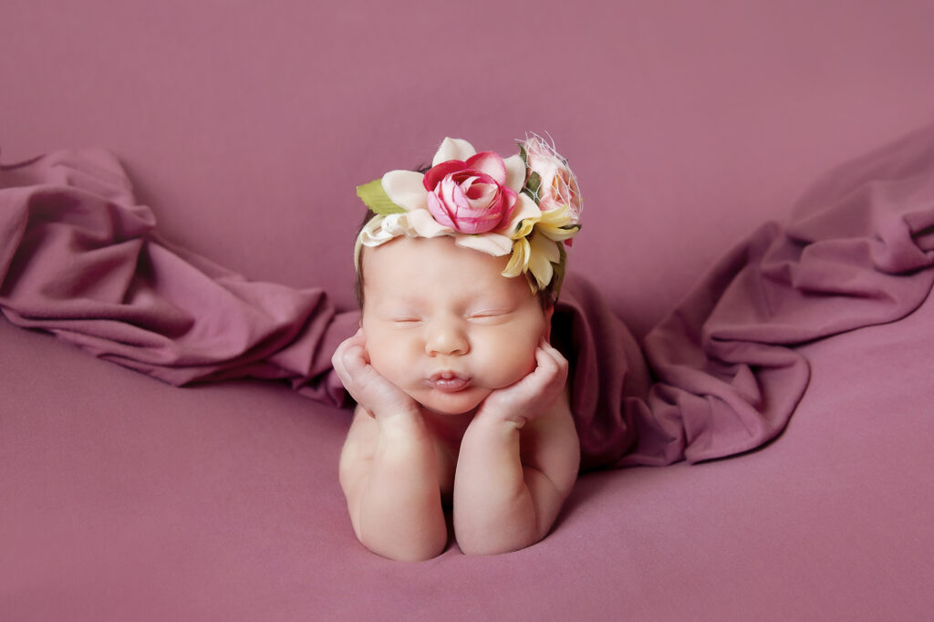 Newborn Baby Froggy pose on a dusy rose blanket taken in a portrait studio in Calgary, Alberta