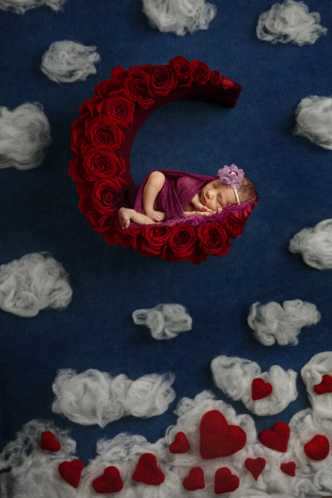 Valentines day newborn photo of a baby hanging on a moon of roses