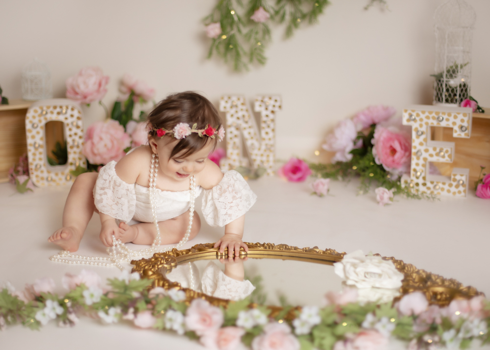 Birthday girl looking at gold vintage mirror with flowers