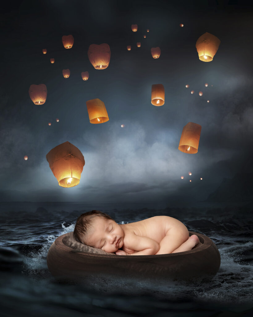 Creative newborn photo of baby laying beside lanterns